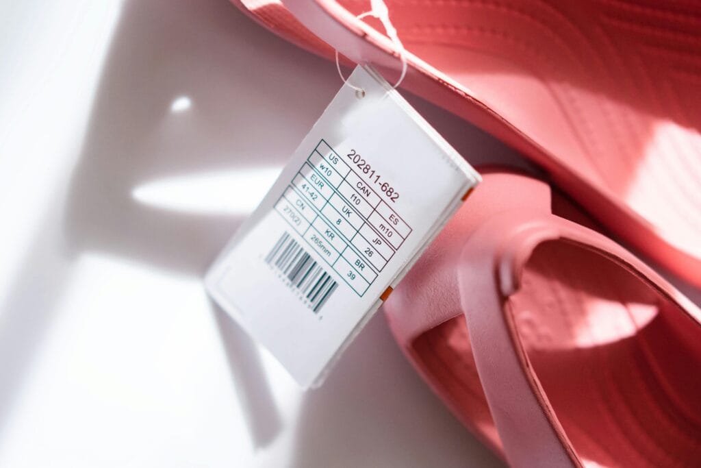 Detailed shot of pink sandals showing size tag and barcode for retail display.