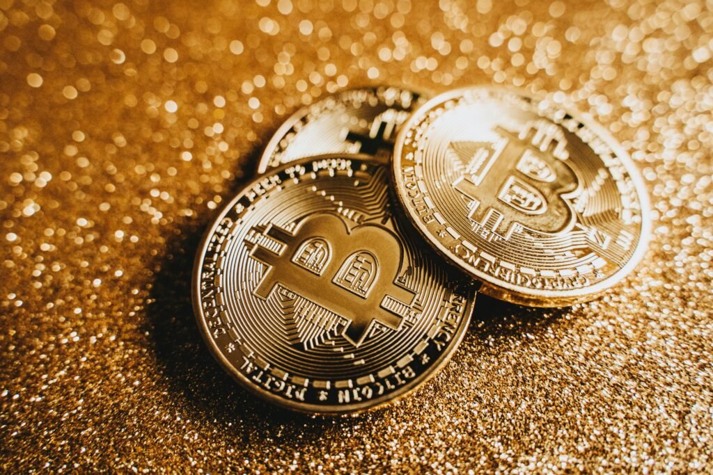 Close-up of shiny bitcoins on a gold glitter background, symbolizing cryptocurrency wealth.